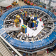 A large blue ring in a warehouse with wires and pipes, used in the muon g-2 calculation.